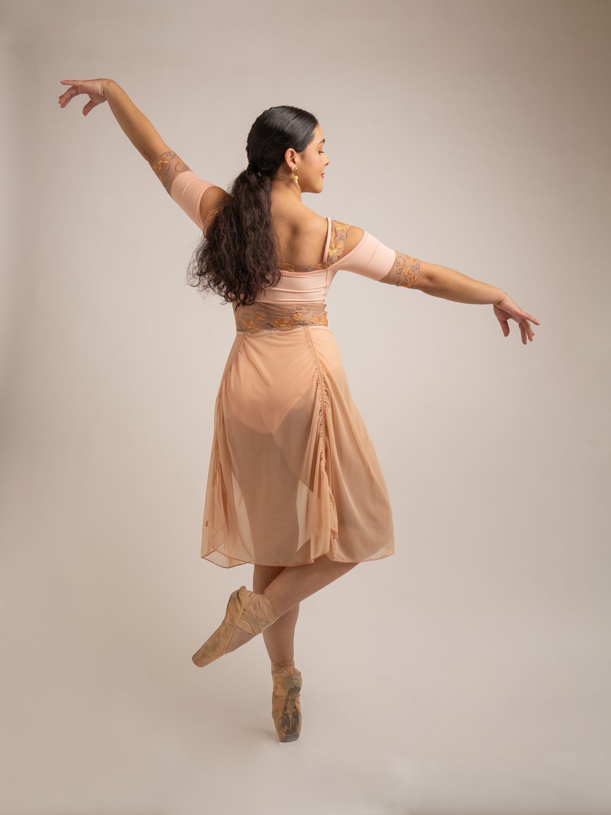 Dancer in a blush drop waist skirt on pointe